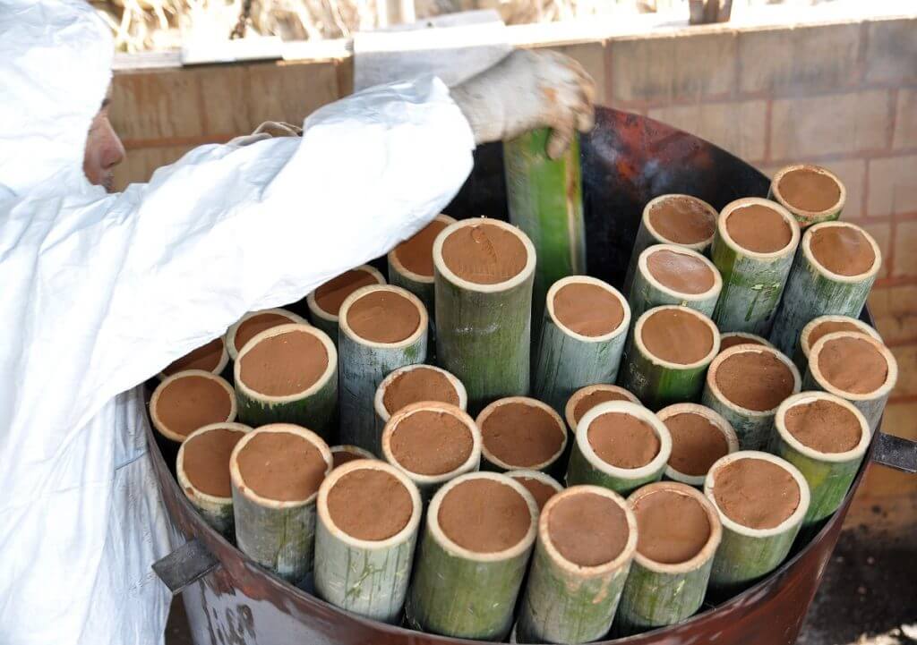 De gevulde bamboekokers met Koreaans zeezout en rode bergklei worden in een ijzeren ton geplaatst.